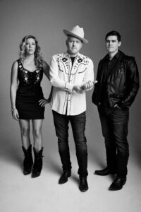 Three band members standing with a black and white filter.