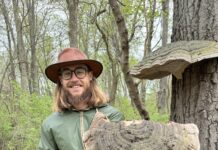 Mushroom Expert and Forager Tyler Davidson Comes to Crazy Wisdom Man in woods holding large mushroom.