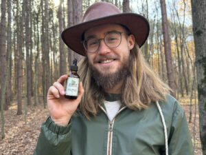 Man in woods holding tincture botle